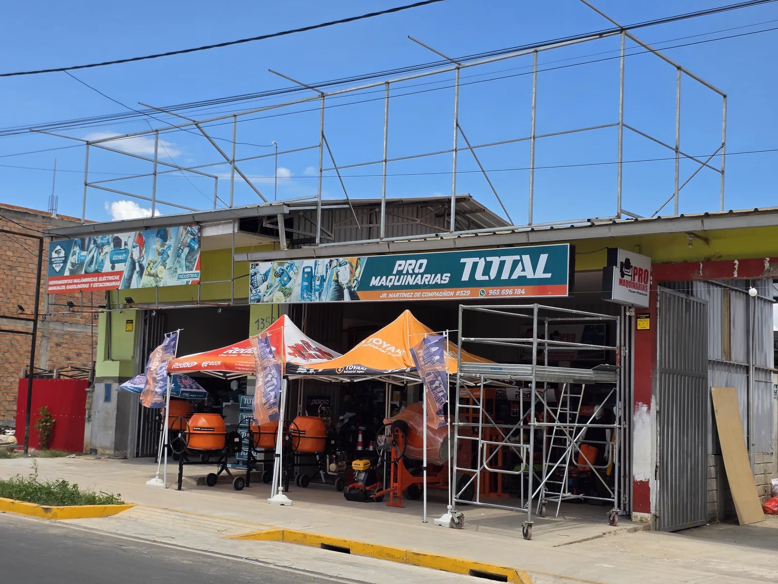 Fachada de la tienda con toldos, trompos y andamio en exhibición